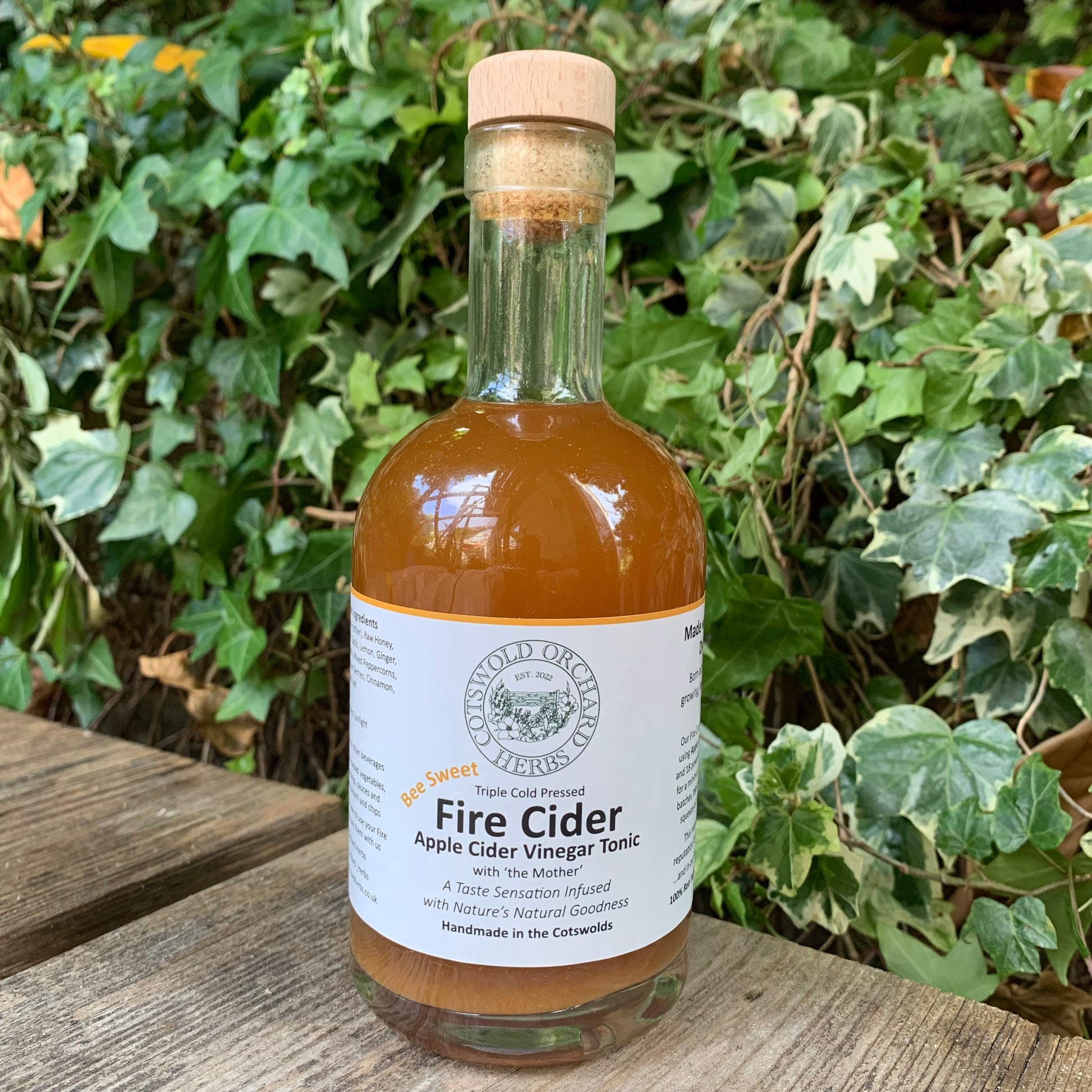 Front-facing Bee Sweet Fire Cider 350ml bottle – triple cold pressed apple cider vinegar tonic infused with natural ingredients, handmade in the Cotswolds, photographed in natural green setting