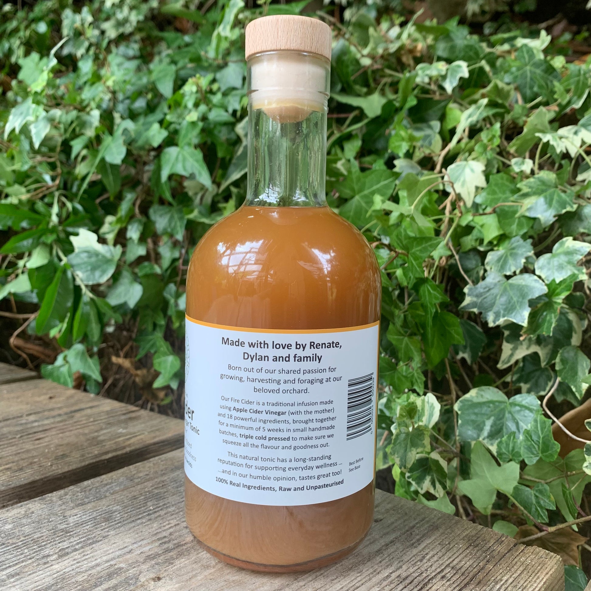 Back of G&T Boost Fire Cider 500ml bottle – label highlighting family story and handcrafted production process, set outdoors against lush ivy foliage