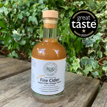 Bottle of Fire Cider on a wooden surface with a 'Great Taste' award logo in the background.