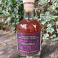 Bottle of Bramble Fire Cider Vinegar on a wooden surface with greenery in the background
