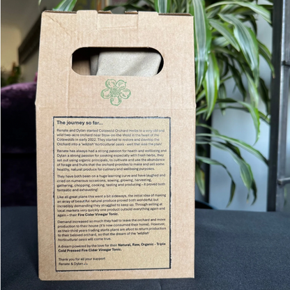 Cardboard box with text and a logo on a surface with a plant in the background
