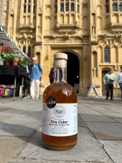 Bottle of Fire Cider vinegar with a label in front of an historic church in the centre of Cirencester.