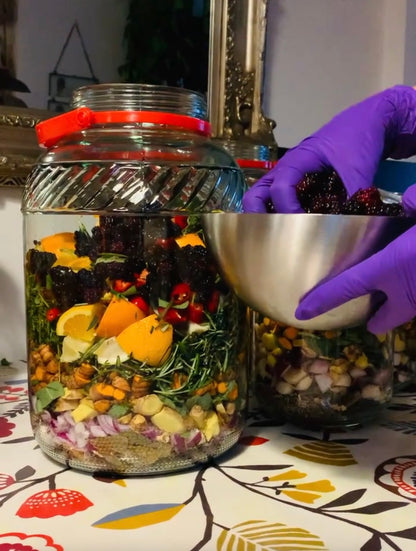 Glass jar filled with a colorful salad and a hand holding a metal bowl on a patterned tablecloth.